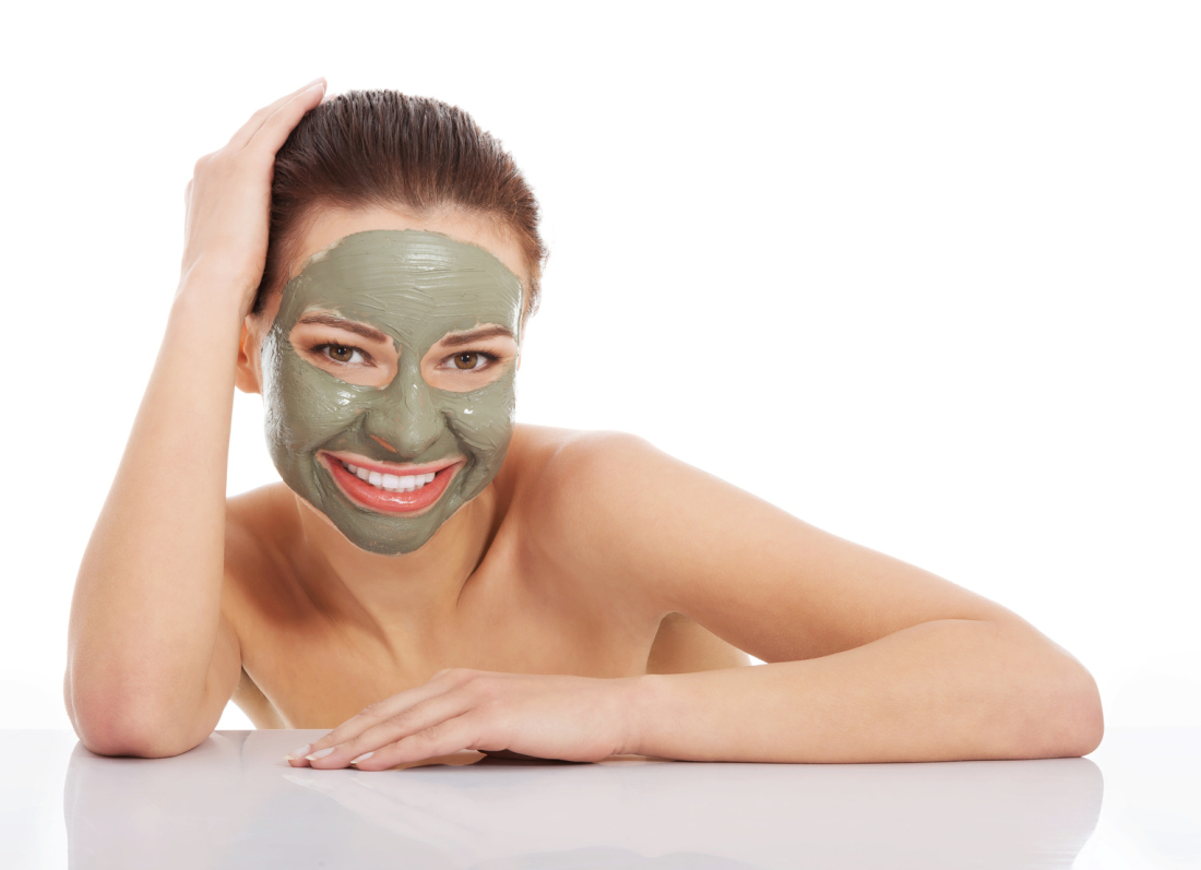 Beautifu toplessl woman with facial mask with hands on table. Isolated on white.